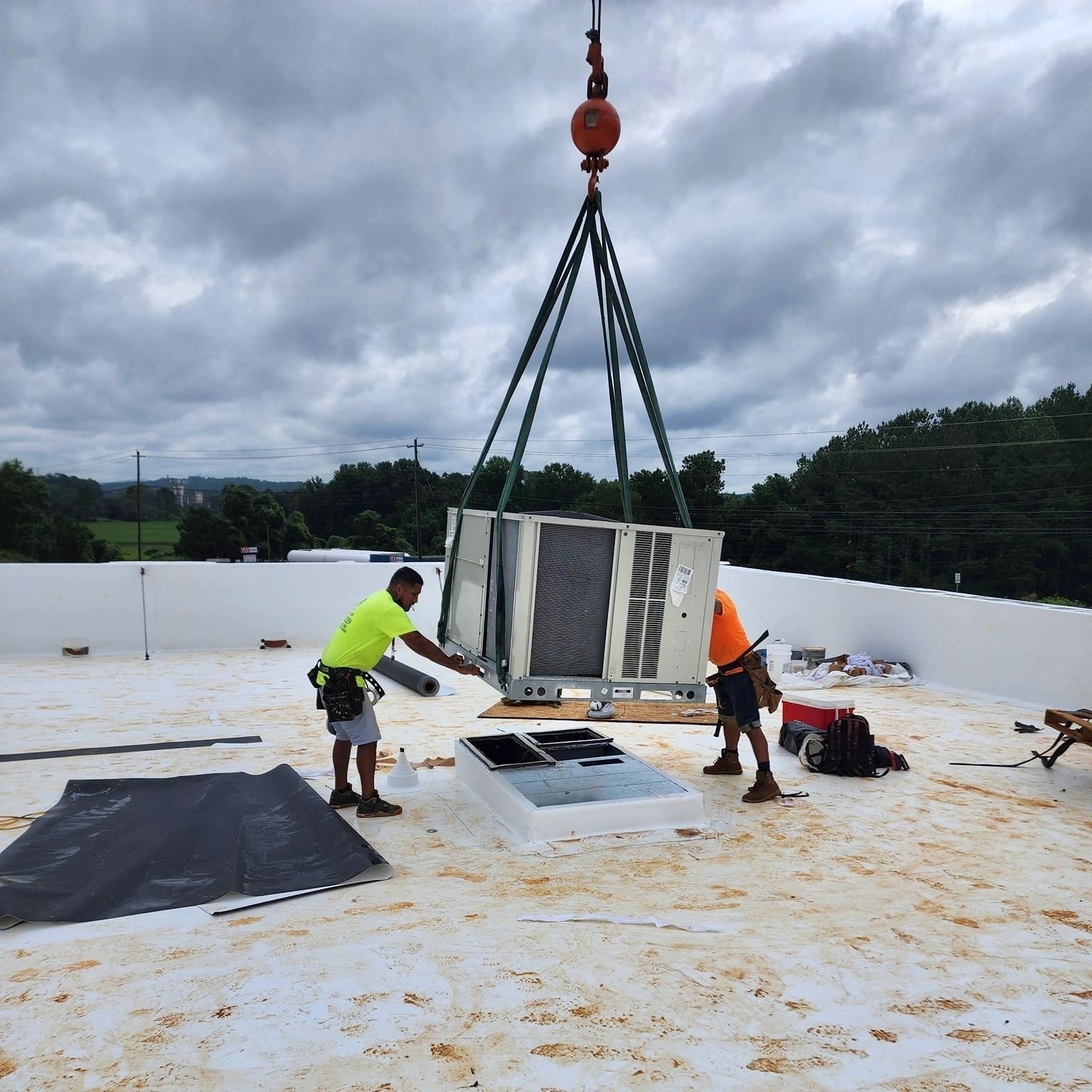 Crane lifting HVAC unit to rooftop