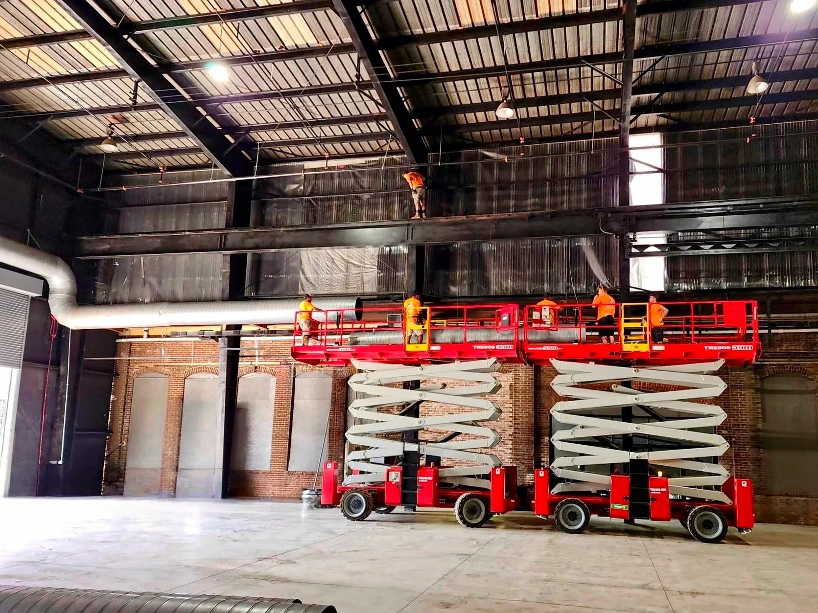 Warehouse ductwork installation with scissor lifts